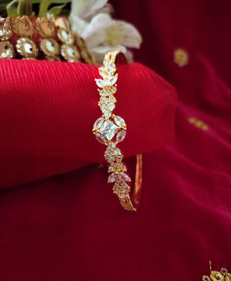B0205_Beguiling flower design golden color bangle style bracelet studded with dazzling american diamond stones with delicate design.