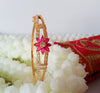 B0195_Lovely golden color bangle style flower design bracelet studded with dazzling american diamond stones with a touch of pink stones.