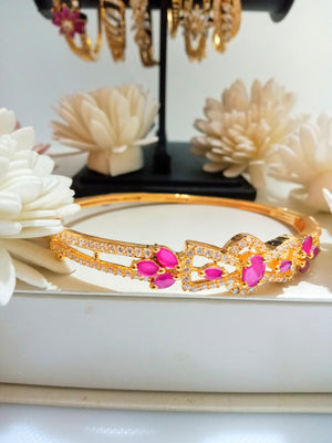 B0191_Lovely golden color bangle style bracelet studded with dazzling american diamond stones with a touch of pink stones.