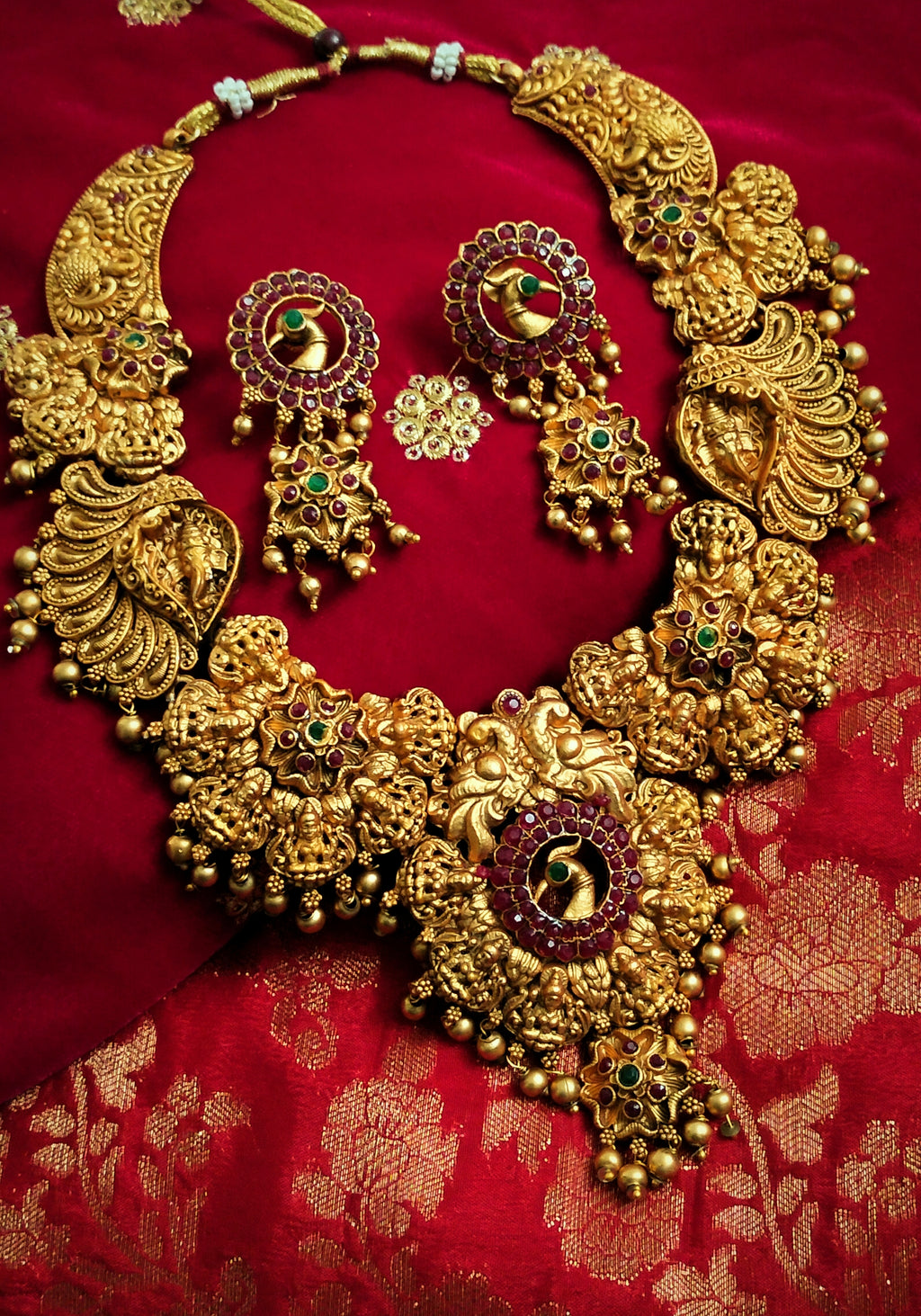 N03069_ Grand classic matte gold polished temple jewelry choker style and Long Haram crafted design gold plated necklace set embellished with ruby and green stones .
