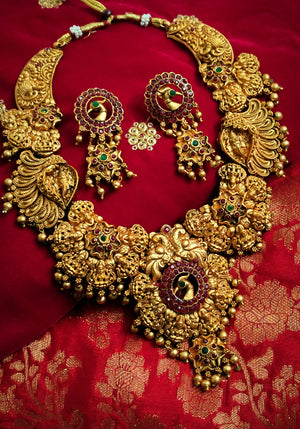 N03069_ Grand classic matte gold polished temple jewelry choker style and Long Haram crafted design gold plated necklace set embellished with ruby and green stones .